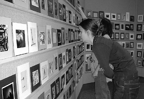 [Woman examines artworks]