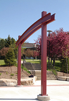 [Rust-coloured metal arch, blue sky]