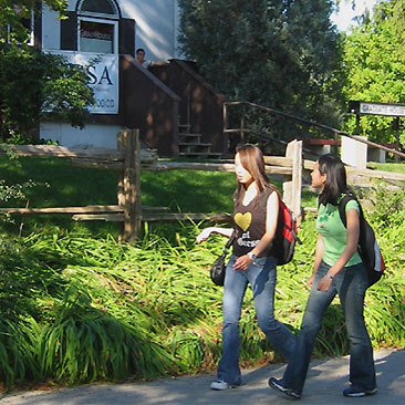 [Two young women walking by the greenery]