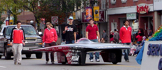 [Students tower over the low car]