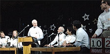 [Johnston as quizmaster; two panels of contestants]