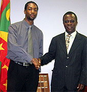 [Shaking hands beside Grenadian flag]