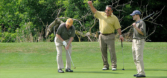 [Three men on green, one waving]