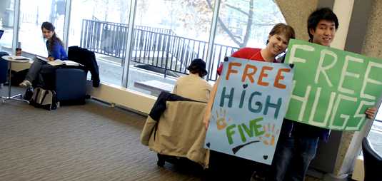 [Two with signs: Free High Fives, Free Hugs; student giving them the eye]