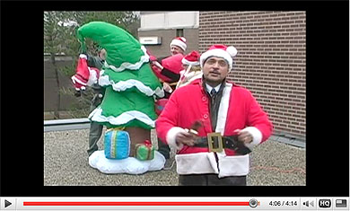 [Saini in red suit beside inflatable tree]