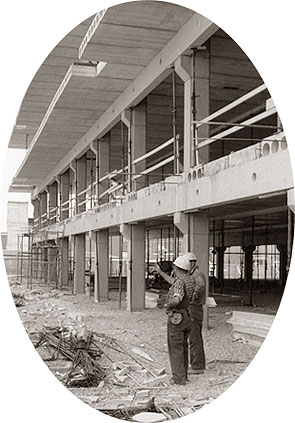 [Workers gesture, beside unfinished concrete]