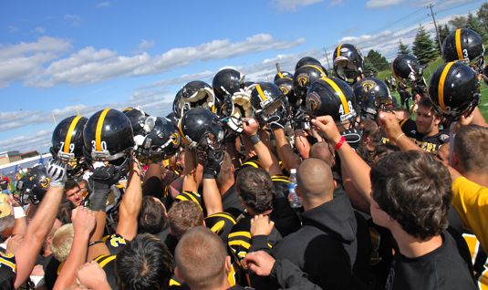 Waterloo football warriors with helmets in air.