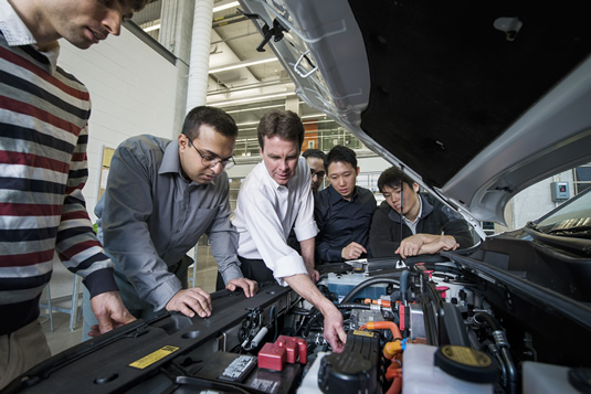 John McPhee and students examine an engine.