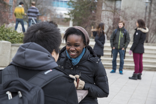 Students sit outside at a table on campus.