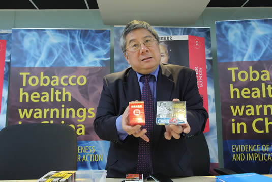 Professor Geoffrey Fong poses with a pair of cigarette packages at the World Health Organization event.