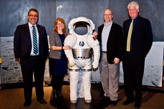 President Hamdullahpur poses with alumni and a space suit.
