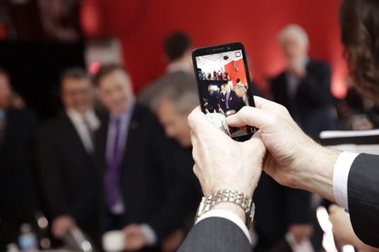 An image of someone taking a cell phone photo of attendees at the Innovation Summit.