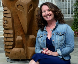 Professor Wendy Fletcher sits next to a totem pole.