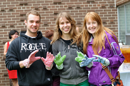Three volunteers wearing gardening gloves at the Community Garden.