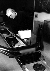 Michael Elmitt peers intently at a rowing shell.