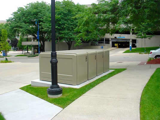 A bank of bike lockers from CycleSafe near a road.