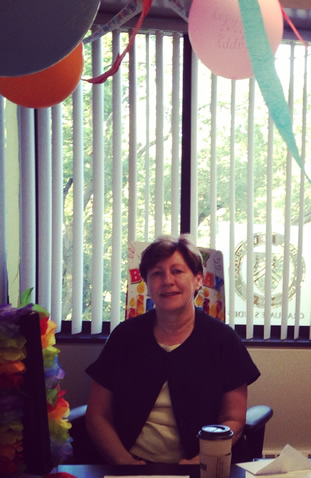 Graduate Studies Office Director Lynne Judge surrounded by birthday bunting.
