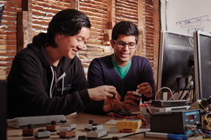Two male Velocity members assemble a piece of electronic gear.