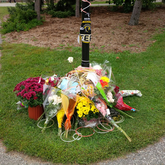 Flowers and other items surround a pole as a memorial for a student killed by lightning last Friday.