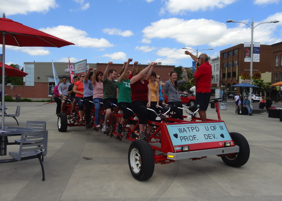 WatPD team members ride a 25-person bike at Waterloo Public Square.